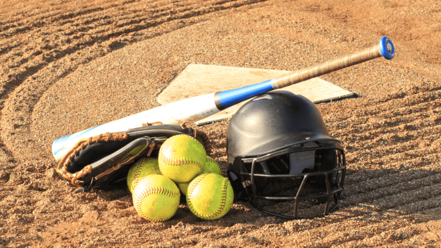 softball balls, bat, glove, and helmet in front of home plate