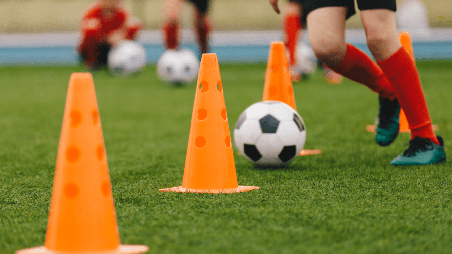 Soccer drill with cones and balls. Legs wearing socks and soccer cleats