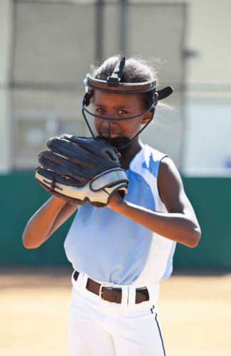 A girl wearing a softball glove with a facemask on
