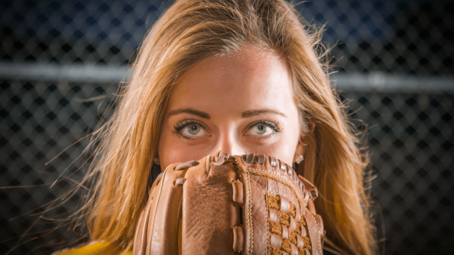 Woman with a softball glove in front of her face